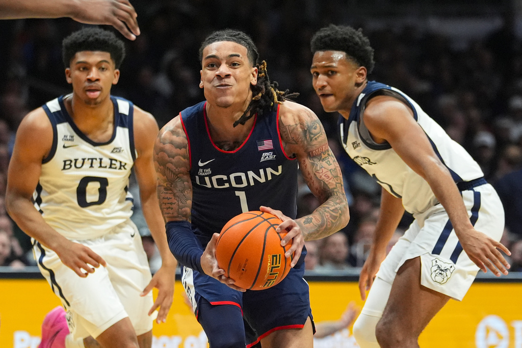 UConn guard Solo Ball (1) cuts between Butler forward Jackson Keith (0) and guard Evan Haywood (1) in the first half of an NCAA college basketball game in Indianapolis, Wednesday, Feb. 11, 2026. (AP Photo/Michael Conroy)
