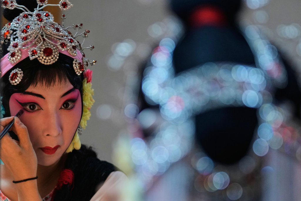 A Peking Opera actress applies makeup backstage before a show in Beijing, China, Sunday, Sept. 7, 2025. (AP Photo/Mahesh Kumar A.)