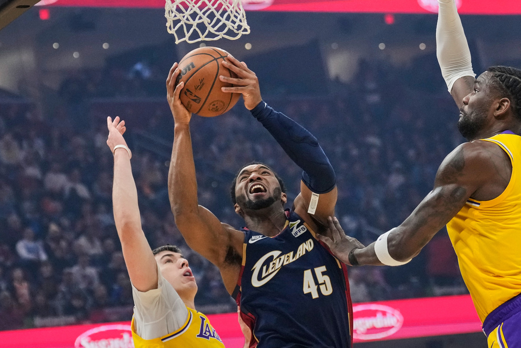 Cleveland Cavaliers guard Donovan Mitchell (45) shoots between Los Angeles Lakers forward Jake LaRavia, left, and center Deandre Ayton, right, in the first half of an NBA basketball game in Cleveland, Wednesday, Jan. 28, 2026. (AP Photo/Sue Ogrocki)