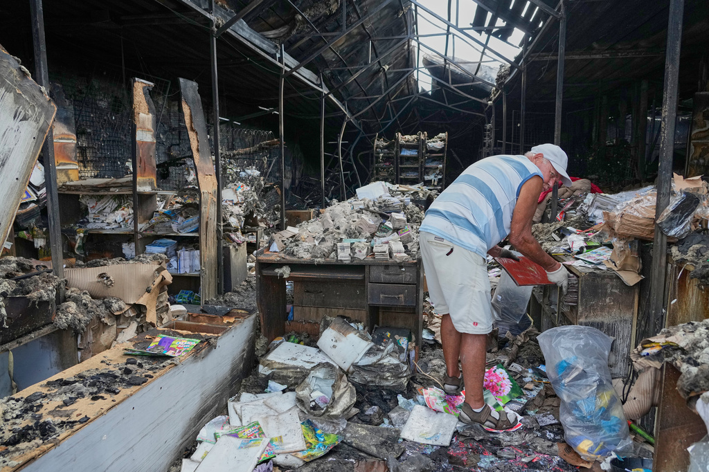 FILE - A man searches burned books after a fire at the country's biggest book market, caused by a Russian recent missile attack in Kyiv, Ukraine, Aug. 19, 2026. (AP Photo/Efrem Lukatsky, File)