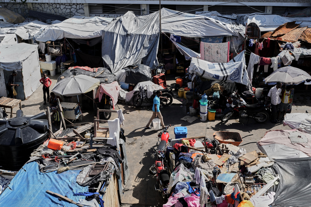 A man carries a buckets of water where families displaced by gang violence are living in Port-au-Prince, Haiti, Wednesday, Aug. 12, 2026. (AP Photo/Odelyn Joseph)