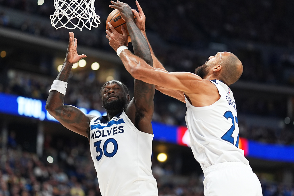 Minnesota Timberwolves forward Julius Randle, left, fights for control of a rebound with center Rudy Gobert in the first half of an NBA basketball game against the Denver Nuggets, Sunday, March 1, 2026, in Denver. (AP Photo/David Zalubowski)