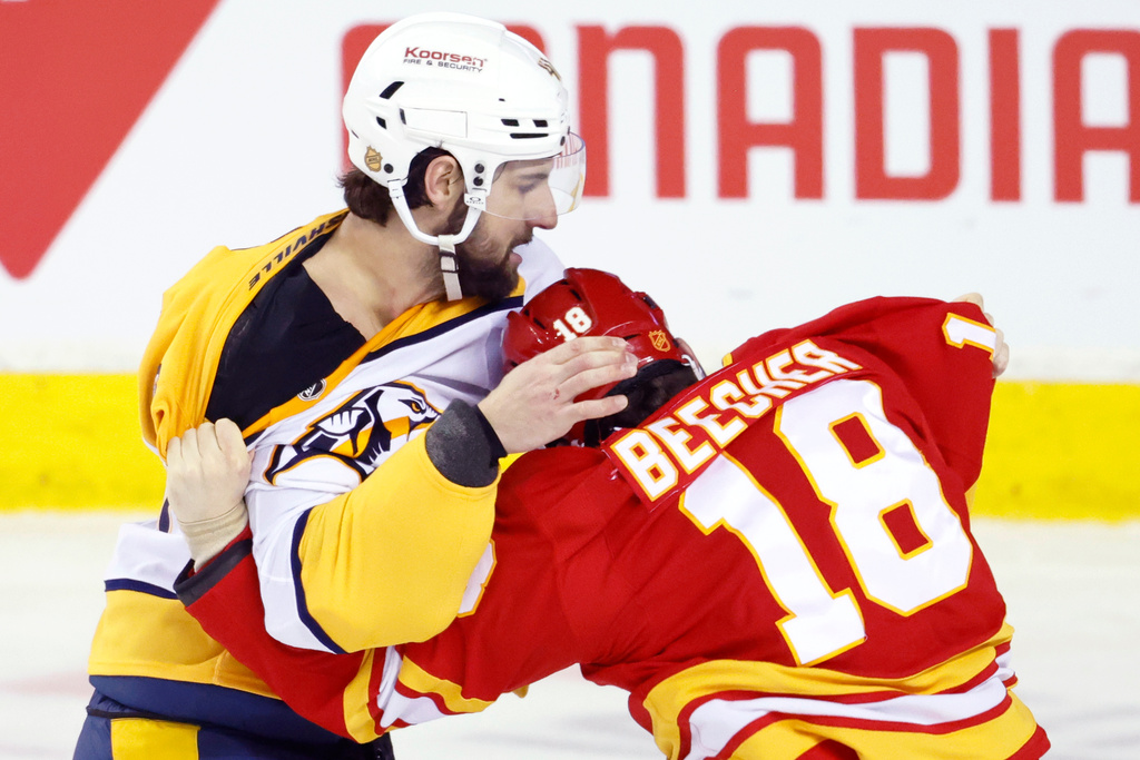 Nashville Predators' Nicolas Hague, left, fights with Calgary Flames' John Beecher during the second period of an NHL hockey game in Calgary, Alberta, Saturday, Jan. 3, 2026. (Larry MacDougal/The Canadian Press via AP)