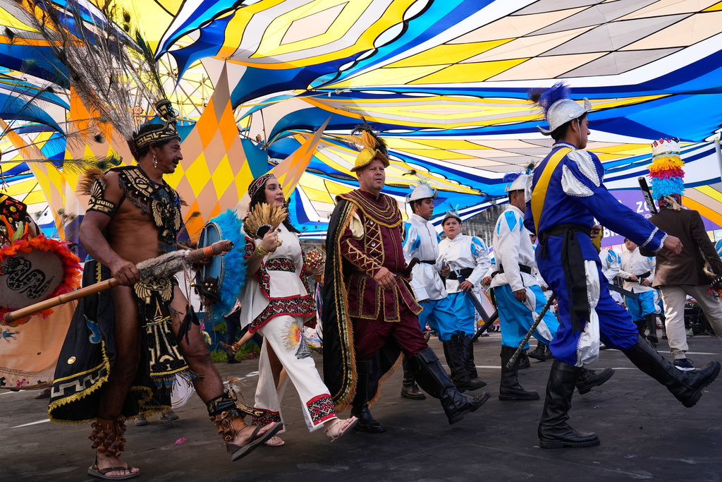 Moctezuma, represented by Gerardo Hernández Espinoza, left, La Malinche, represented by Ximena Isabel Ochoa López, center, and Hernán Cortez, represented by José Antonio Ochoa Lopez take part in a pre-Hispanic dance in the Zocalo, in Mexico City, Sunday, Oct. 12, 2025. (AP Photo/Marco Ugarte)