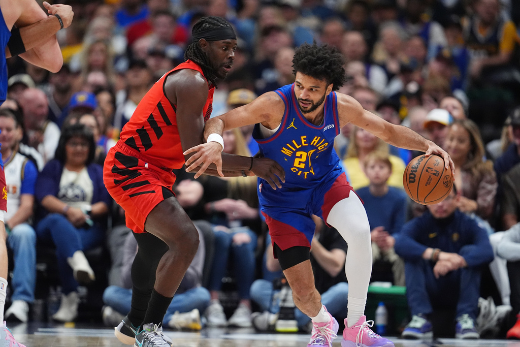 Denver Nuggets guard Jamal Murray, right, drives past Portland Trail Blazers guard Jrue Holiday, left, in the first half of an NBA basketball game Sunday, March 22, 2026, in Denver. (AP Photo/David Zalubowski)