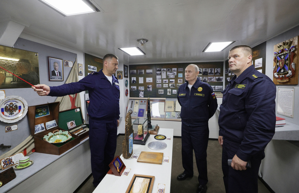 Russian President Vladimir Putin, center, listens to a navy officer as he visits the Varyag missile cruiser of the Pacific Fleet to watch a military exercise near Yuzhno-Sakhalinsk, on Sakhalin Island, Russia, Wednesday, Aug. 12, 2026, as Admiral Viktor Liina, right, looks on. (Gavriil Grigorov, Sputnik, Kremlin Pool Photo via AP)
