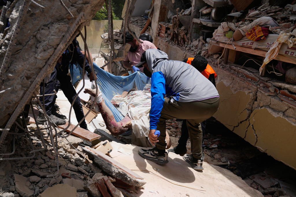 Residents pull a body from the rubble two days after earthquakes struck La Guaira, Venezuela, Friday, June 26, 2026. (AP Photo/Ariana Cubillos)