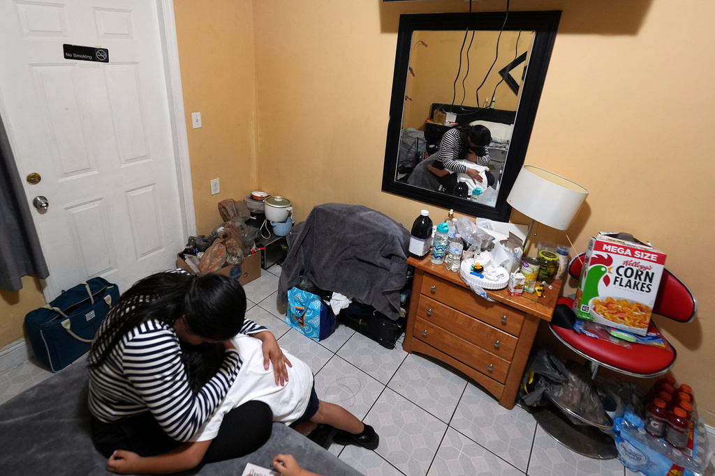 Jakelin Pasedo, 39, hugs her five-year-old son inside the Miami-area motel room where she lives with her two children, who all have refugee status, Wednesday, Oct. 22, 2025, after their father requested to be sent back to Venezuela after months in immigration detention. (AP Photo/Rebecca Blackwell)