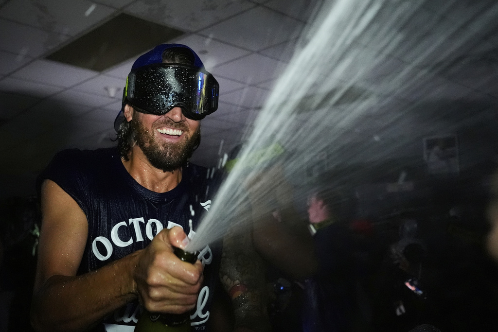 Toronto Blue Jays' Kevin Gausman celebrates with teammates in the clubhouse after their baseball game against the Kansas City Royals, Sunday, Sept. 21, 2025, in Kansas City, Mo. (AP Photo/Charlie Riedel)