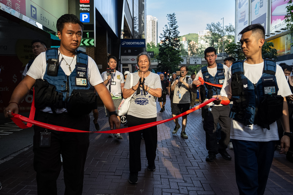 Police officers escort activist Lui Yuk-lin as she prays in the Causeway Bay area on the 37th anniversary of China's Tiananmen Square crackdown, in Hong Kong, Thursday, June 4, 2026. (AP Photo/Chan Long Hei)