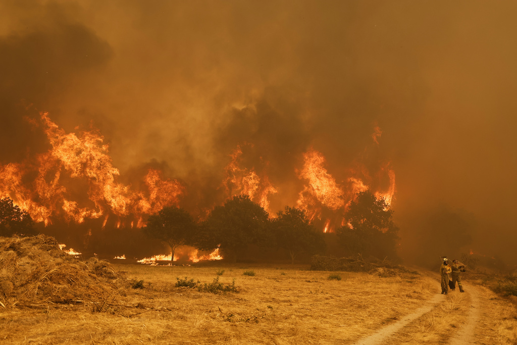 Firefighters stand in front of the flames during a wildfire in Santa Baia De Montes, northwestern Spain, Thursday, Aug. 14, 2025. (AP Photo/Lalo R. Villar)