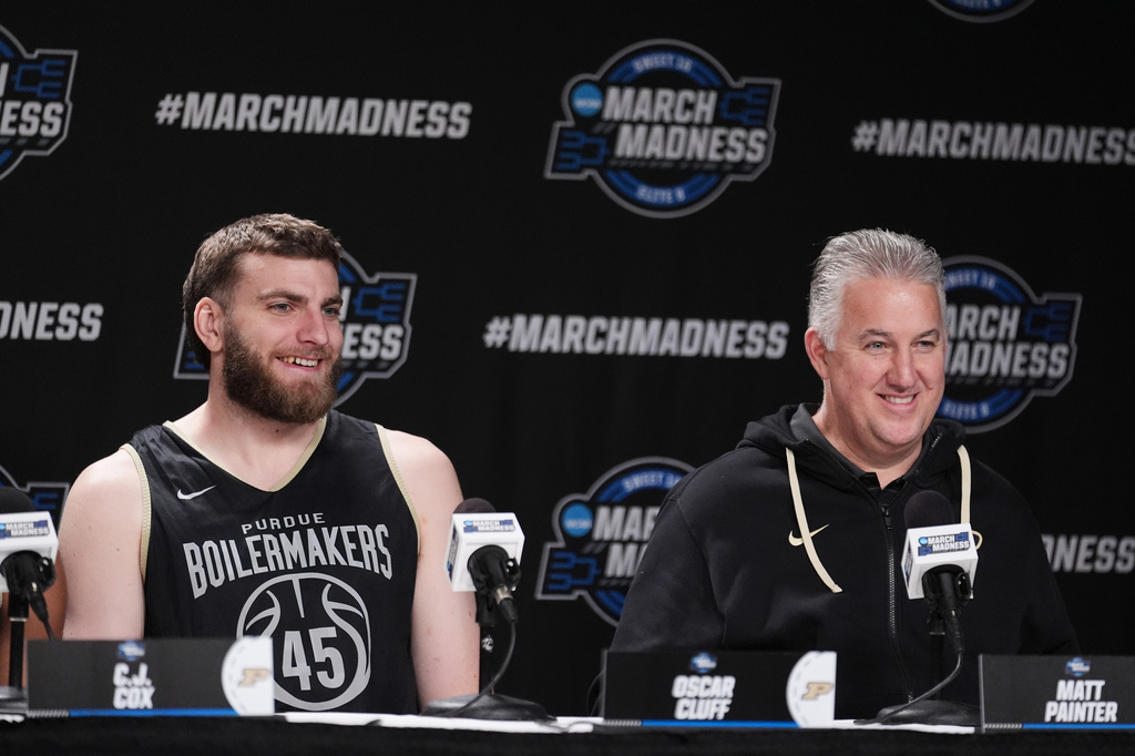 Purdue center Oscar Cluff, left, and head coach Matt Painter answer questions during a press conference ahead of a game against Arizona in the Elite Eight of the NCAA college basketball tournament Friday, March 27, 2026, in San Jose, Calif. (AP Photo/Marcio Jose Sanchez)