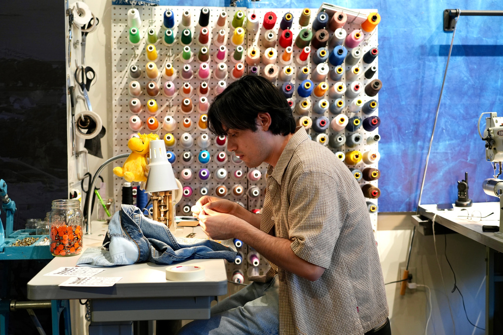Genaro Ruiz sews clothing during a clothing repair workshop at a Levi's retail store in downtown San Francisco on July 22, 2026. (AP Photo/Terry Chea)