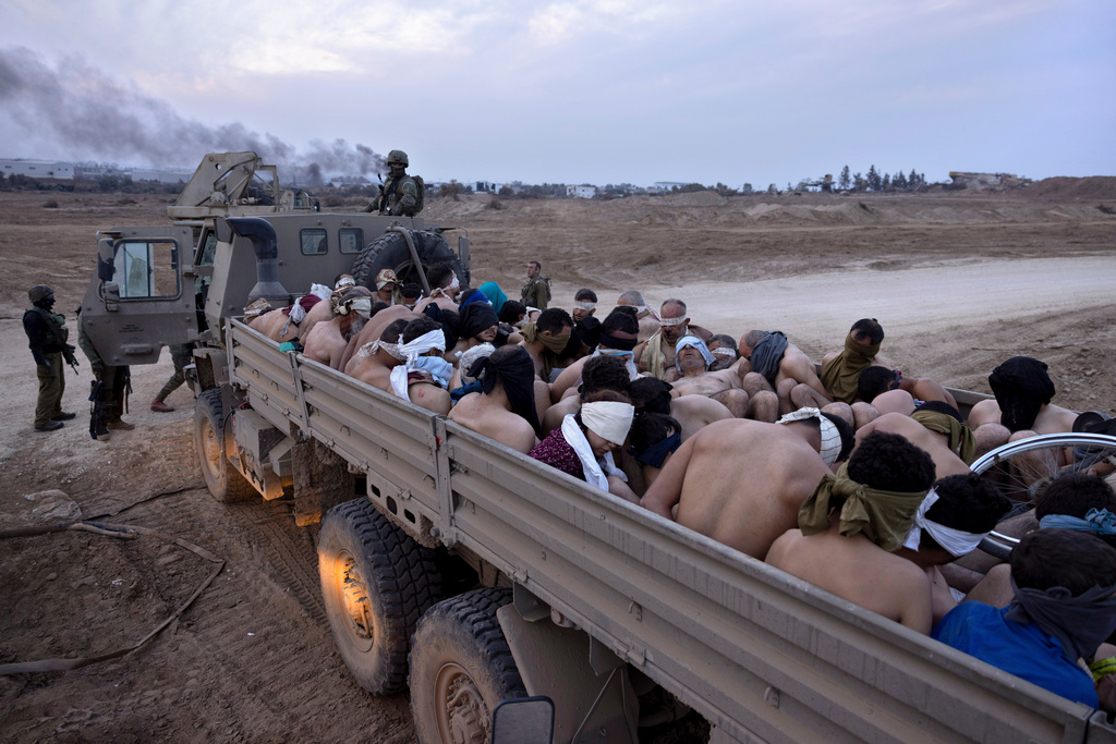 Israeli soldiers stand by a truck packed with bound and blindfolded Palestinian detainees, in Gaza, Friday, Dec. 8, 2023. (Moti Milrod/Haaretz via AP)