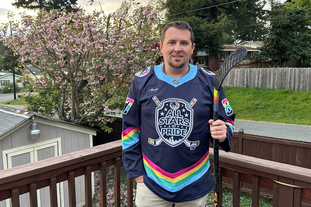 Steven Thompson, co-founder of the Seattle Pride Hockey Association (SPHA), poses for a photo with his stick that features pride tape and a SPHA sweater at his home in Des Moines, Wash., Monday, April 27, 2026. (AP Photo/Andrew Destin)