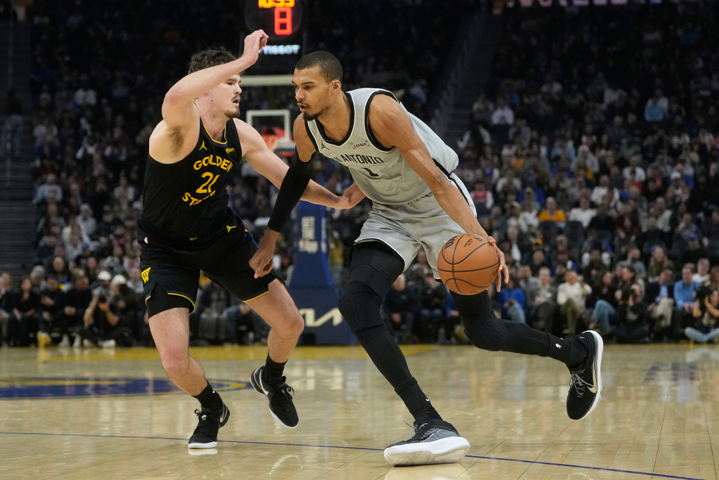 San Antonio Spurs center Victor Wembanyama, right, drives to the basket against Golden State Warriors center Quinten Post during the first half of an NBA basketball game in San Francisco, Wednesday, Feb. 11, 2026. (AP Photo/Jeff Chiu)