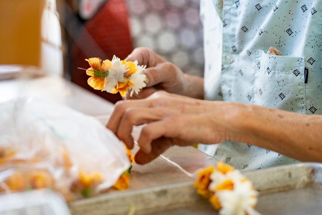 Sam Say, owner of M.P. Lei Shop, strings flowers to make a lei at his shop in Chinatown, Thursday, Feb. 26, 2026, in Honolulu. (AP Photo/Mengshin Lin)