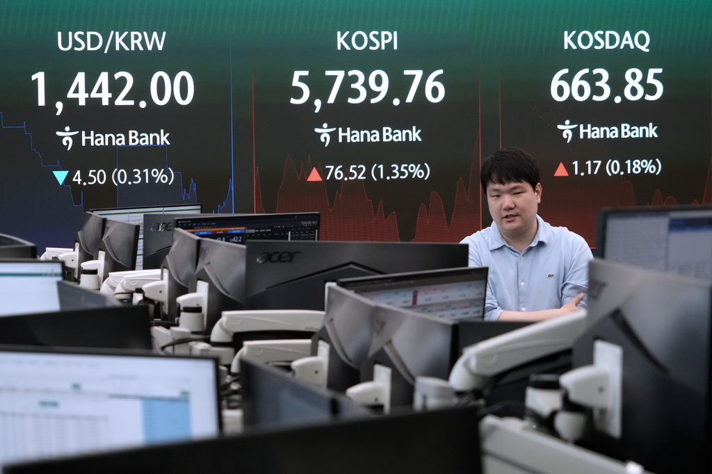A currency trader passes by a screen showing the Korea Composite Stock Price Index (KOSPI) and the foreign exchange rate between U.S. dollar and South Korean won at the foreign exchange dealing room of the Hana Bank headquarters in Seoul, South Korea, Thursday, July 30, 2026. (AP Photo/Ahn Young-joon)