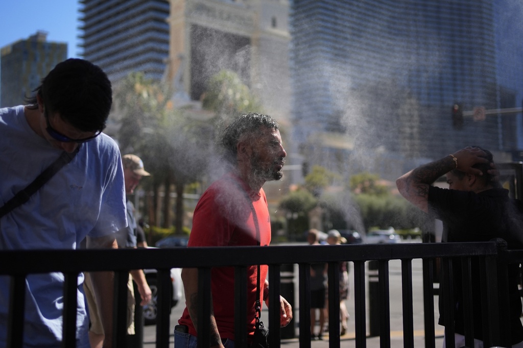 FILE - People cool off in misters along the Las Vegas Strip, Sunday, July 7, 2024, in Las Vegas. (AP Photo/John Locher, File)