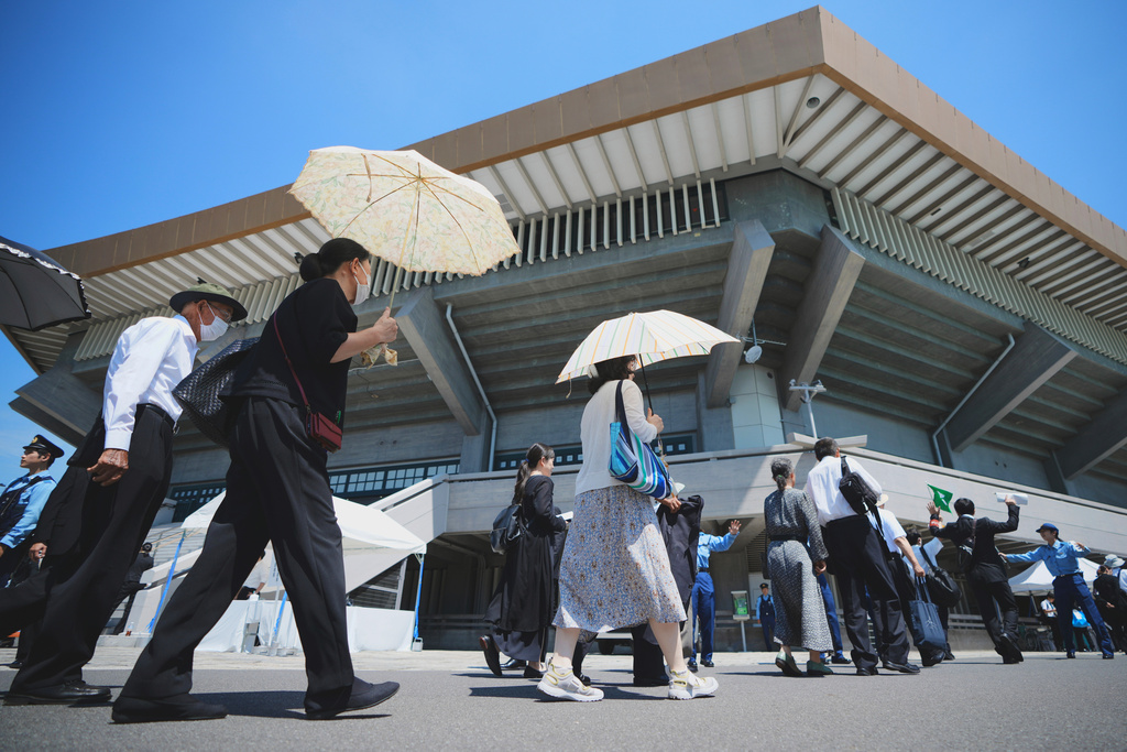 Guests queue to attend a memorial service marking the 80th anniversary of Japan's World War II defeat, at the Nippon Budokan hall Friday, Aug. 15, 2025, in Tokyo. (AP Photo/Eugene Hoshiko)