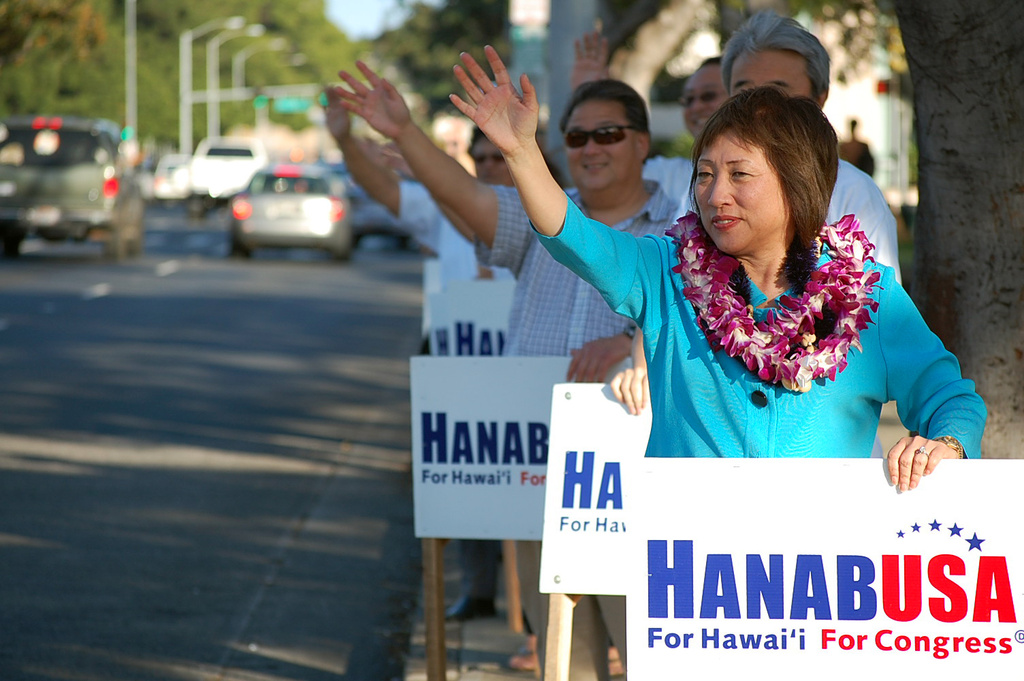 FILE - State Senate President Colleen Hanabusa holds a campaign sign as she waves on South King Street in Honolulu, Monday, March 22, 2010. (AP Photo/Herbert Sample, File)
