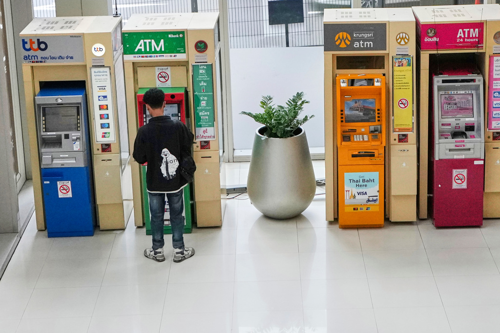 A man uses an ATM machines in Bangkok, Thailand, Wednesday, Aug. 20, 2025. (AP Photo/Sakchai Lalit)