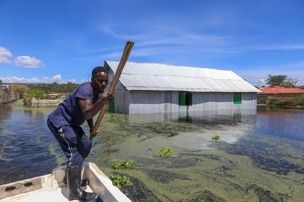 A man paddles a boat next to flooded buildings after Lake Naivasha swelled and inundated homes, displacing hundreds in Kihoto Village in Naivasha, Kenya's Rift Valley region, Tuesday, Nov. 11, 2025. (AP Photo/Andrew Kasuku)