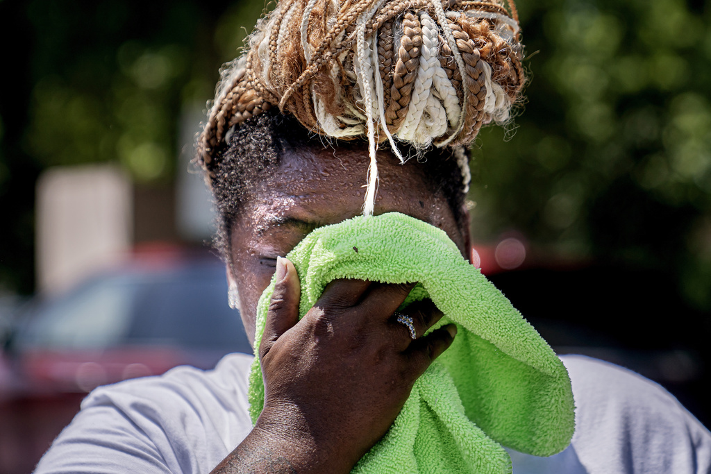 FILE - Nicole Brown wipes sweat from her face while setting up her beverage stand near the National Mall on July 22, 2022, in Washington. (AP Photo/Nathan Howard, File)