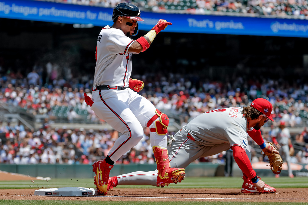 Atlanta Braves' Ronald Acuna Jr., left, runs out an infield single ahead of the throw to Philadelphia Phillies first baseman Bryce Harper, right, during the first inning of a baseball game, Sunday, April 26, 2026, in Atlanta. (AP Photo/Erik S. Lesser)