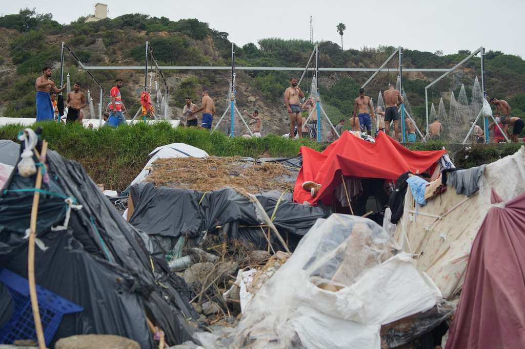 Migrants take a shower near their tents at El Trampolín beach in the Spanish exclave of Ceuta, Wednesday, Sept. 2, 2026. (AP Photo/Francis González)