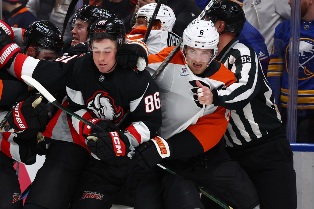 Buffalo Sabres center Noah Ostlund (86) and Philadelphia Flyers defenseman Travis Sanheim (6) get separated by linesman Matt MacPherson (83) during the second period of an NHL hockey game Thursday, Dec. 18, 2025, in Buffalo, N.Y. (AP Photo/Jeffrey T. Barnes)