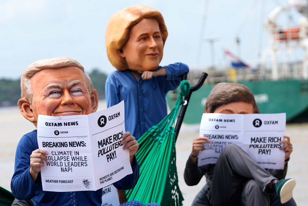 Oxfam activists wear puppet heads in the likeness of U.S. President Donald Trump, left, President of the European Commission Ursula von der Leyen, center, and President of Argentina Javier Milei as they protest ahead of the COP30 U.N. Climate Summit in Belem, Para state, Brazil, Wednesday, Nov. 5, 2025. (AP Photo/Eraldo Peres)