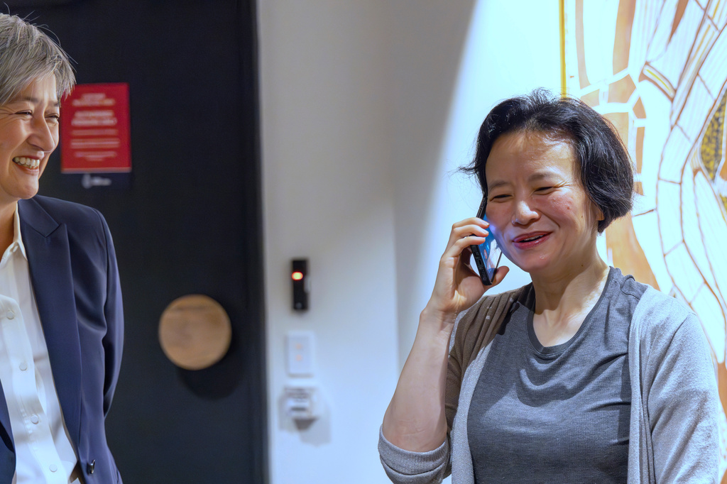 FILE - In this photo provided by the Department of Foreign Affairs and Trade, Chinese Australian journalist Cheng Lei, right, talks on the phone as Australia's Minister for Foreign Affairs, Penny Wong, watches at Tullamarine Airport in Melbourne, on Wednesday Oct. 11, 2023. (Sarah Hodges/DFAT via AP, FILE)