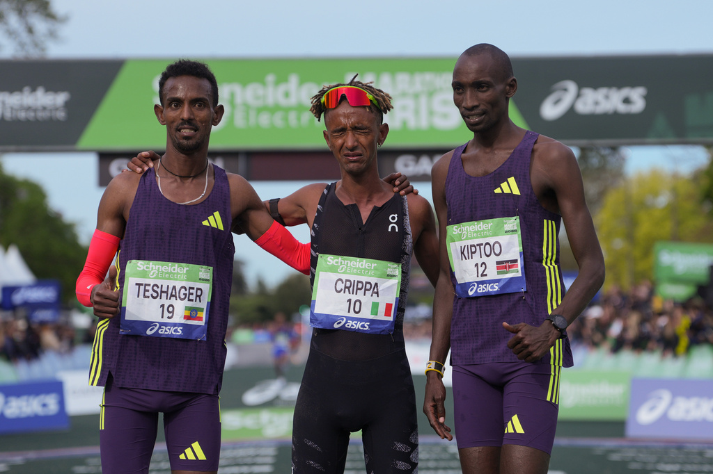 From left, Ethiopia's Bayelign Teshager, Italy's Yemaneberhan Crippa and Kenya's Sila Kiptoo pose after crossing the finish line of the men's race of the Paris marathon, in Paris, Sunday, April 12, 2026. (AP Photo/Thibault Camus)