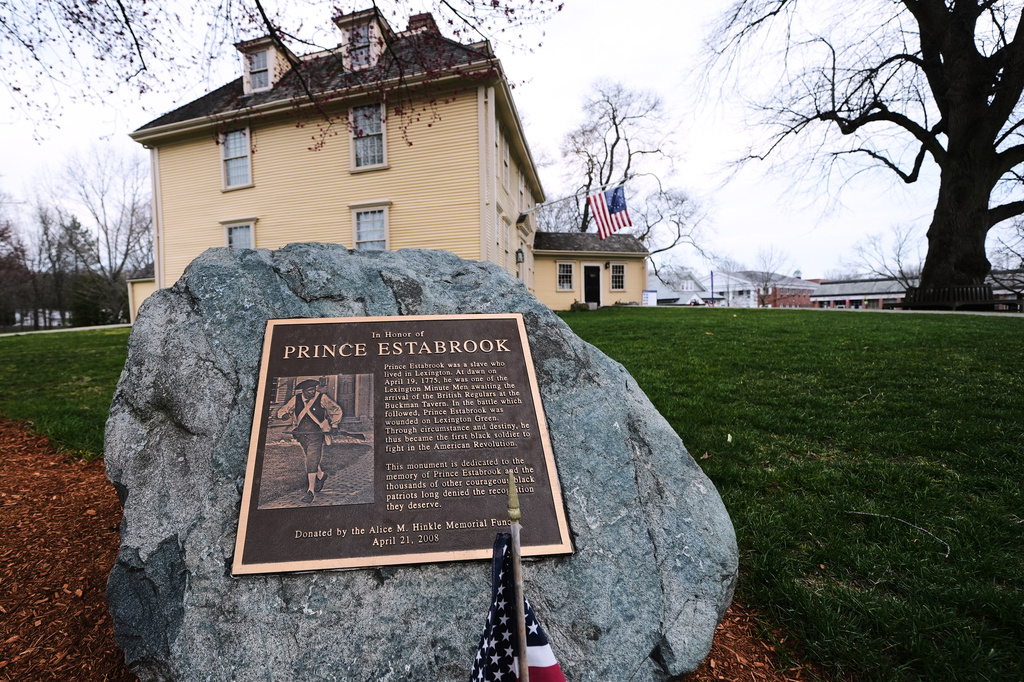 A memorial for enslaved Minuteman Prince Estabrook, which features an image of Revolutionary War re-enactor and Korean War veteran Charles Price, is displayed near the village green, Monday, April 13, 2026, in Lexington, Mass. (AP Photo/Charles Krupa)