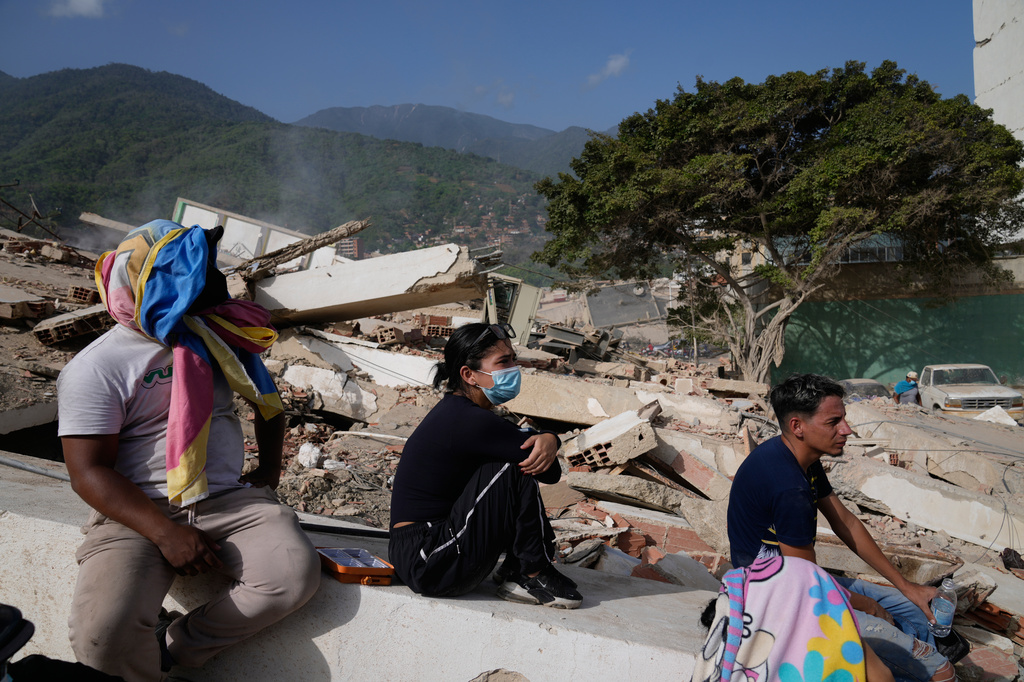 Residents sit near their destroyed homes two days after an earthquake struck La Guaira, Venezuela, Friday, June 26, 2026. (AP Photo/Ariana Cubillos)