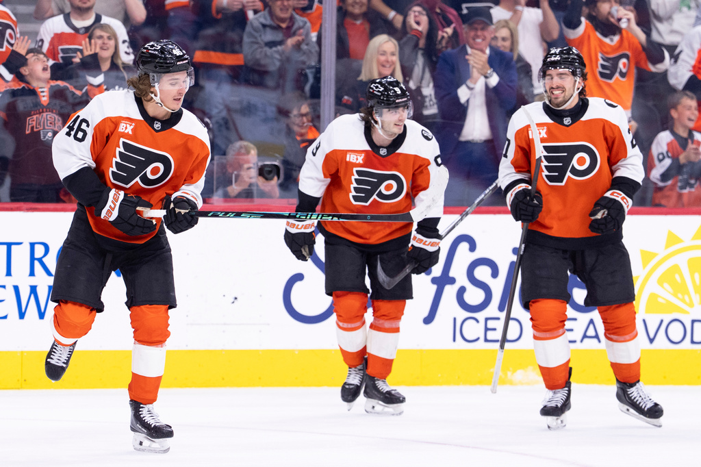 Philadelphia Flyers center Trevor Zegras, left, celebrates with defenseman Jamie Drysdale, center, and left winger Noah Cates, right, after his goal during the second period of an NHL hockey game against the Carolina Hurricanes, Monday, April 13, 2026, in Philadelphia. (AP Photo/Chris Szagola)