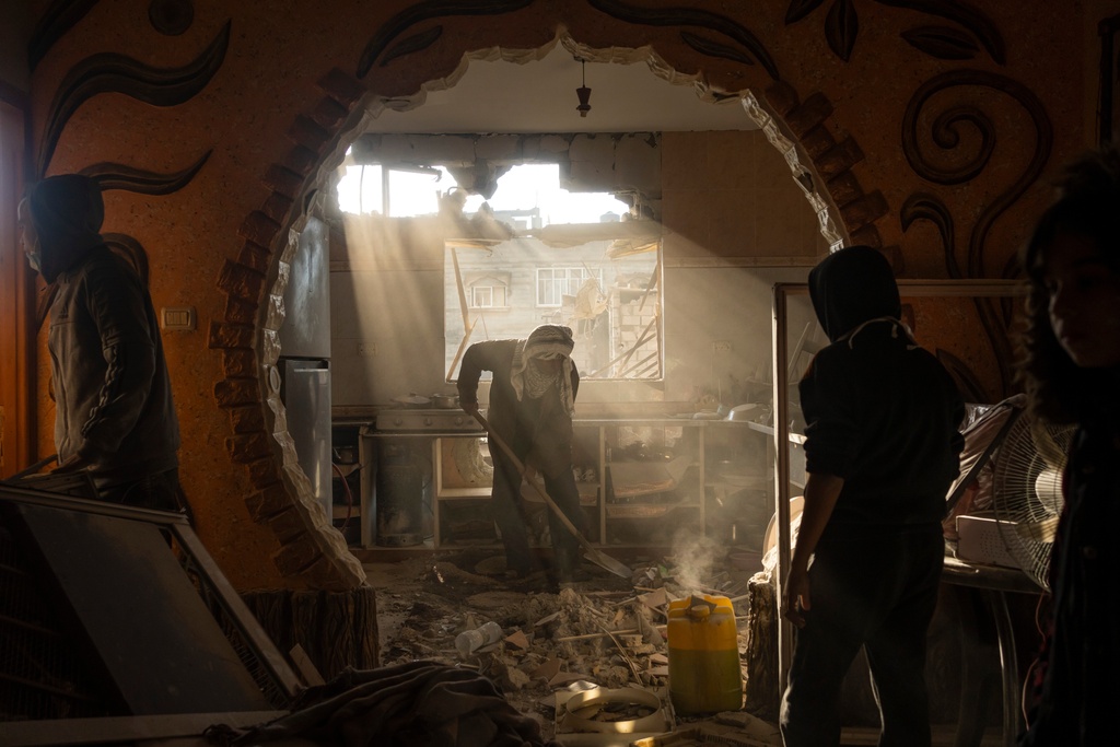 People look at their neighbor's damaged house following an Israeli strike in Rafah, southern Gaza Strip, Saturday, Jan. 27, 2024. (AP Photo/Fatima Shbair)