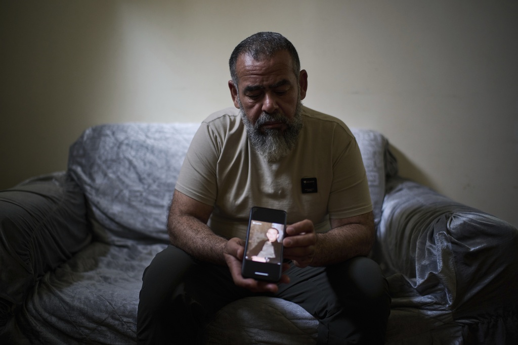 Ashraf Gharbieh, 45, holds a phone showing a photo of his 14-year-old son, Mahmoud Gharbieh, who was killed in an Israeli airstrike in the Jenin refugee camp, as he sits for a portrait at a friend's house on the outskirts of the West Bank city of Jenin, April 21, 2025. (AP Photo/Leo Correa)