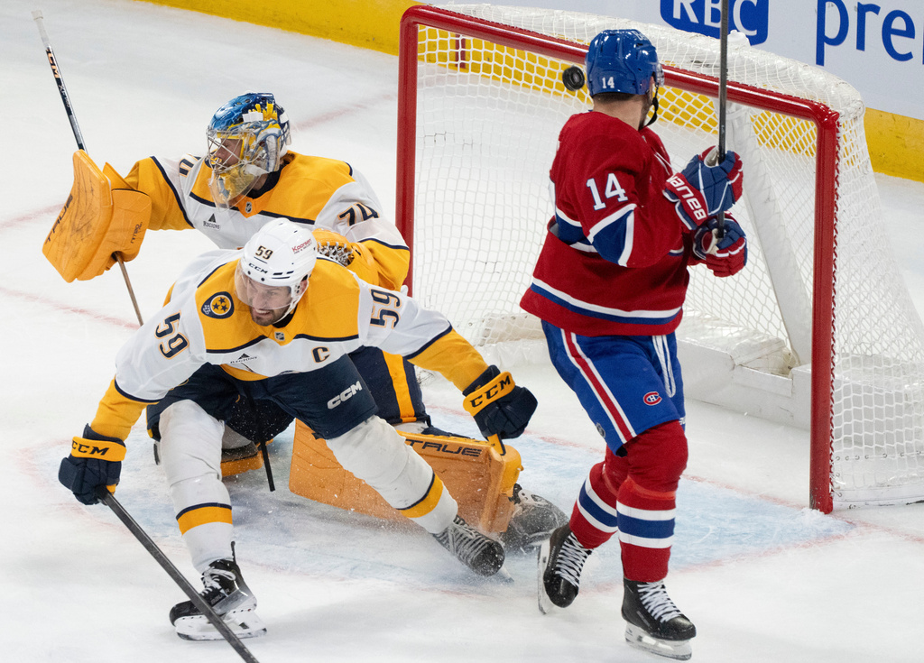 Montreal Canadiens' Nick Suzuki (14) watches as a shot by teammate Montreal Canadiens' Cole Caufield (not shown) goes into the net past Nashville Predators goaltender Juuse Saros (74) and Roman Josi (59) during overtime NHL hockey action in Montreal on Thursday, Oct. 16, 2025. (Christinne Muschi/The Canadian Press via AP)