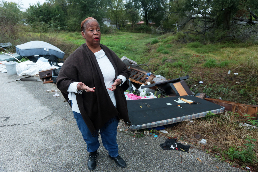 Huey German-Wilson, Trinity-Houston Community President, is interviewed near large piles of trash and debris littering a narrow roadway in the Trinity Gardens neighborhood in northwest Houston, Thursday, Dec. 4, 2025. (AP Photo/Lekan Oyekanmi )