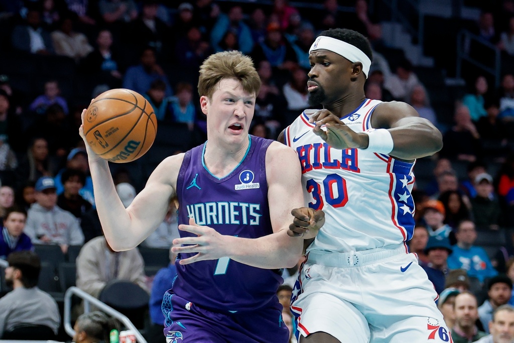 Charlotte Hornets guard Kon Knueppel, left, passes against Philadelphia 76ers center Adem Bona (30) during the first half of an NBA basketball game in Charlotte, N.C., Monday, Jan. 26, 2026. (AP Photo/Nell Redmond)