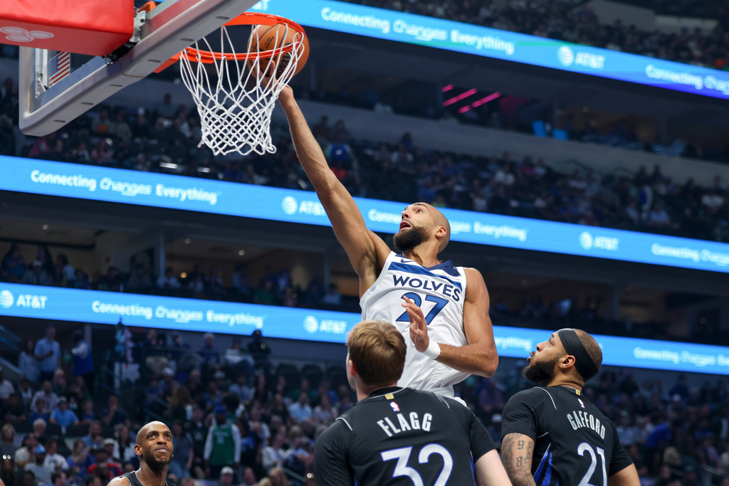 Minnesota Timberwolves center Rudy Gobert (27) scores past Dallas Mavericks forwards Daniel Gafford (21) and Cooper Flagg (32) in the first half of an NBA basketball game Monday, March 30, 2026, in Dallas. (AP Photo/Gareth Patterson)