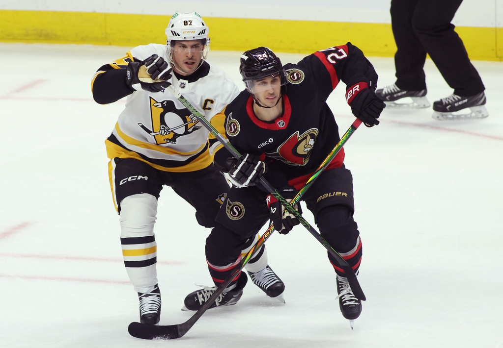 Pittsburgh Penguins' Sidney Crosby (87) battles with Ottawa Senators' Dylan Cozens (24) during the first period of an NHL hockey game in Ottawa, Ontario, Thursday, Dec. 18, 2025. (Patrick Doyle/The Canadian Press via AP)