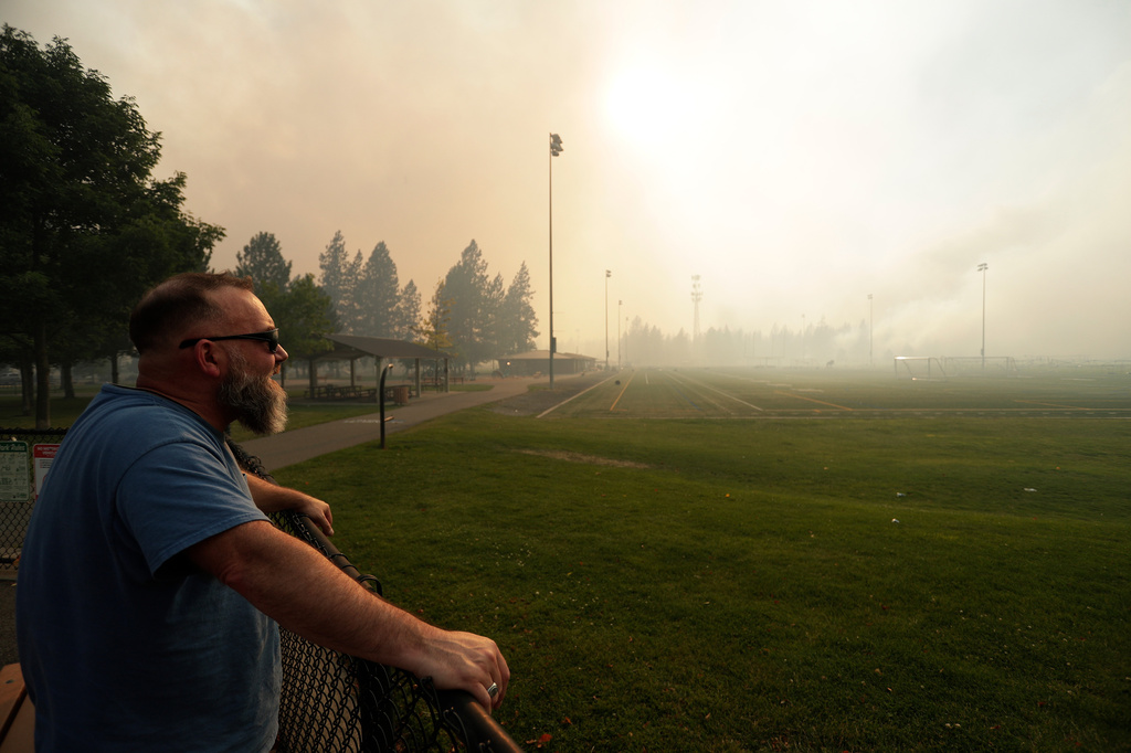 Andrew Rowley watches Old Trails Fire from Dwight Merkel Sports Complex after evacuating, Saturday, Aug. 1, 2026, in Spokane, Wash. (AP Photo/Young Kwak)