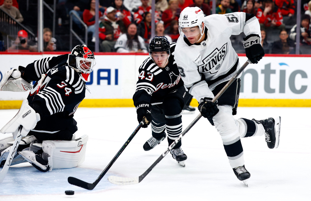 New Jersey Devils goaltender Jake Allen (34) and defenseman Luke Hughes (43) defend against Los Angeles Kings right wing Jared Wright (53) during the first period of an NHL hockey game, Saturday, March 14, 2026, in Newark, N.J. (AP Photo/Noah K. Murray)