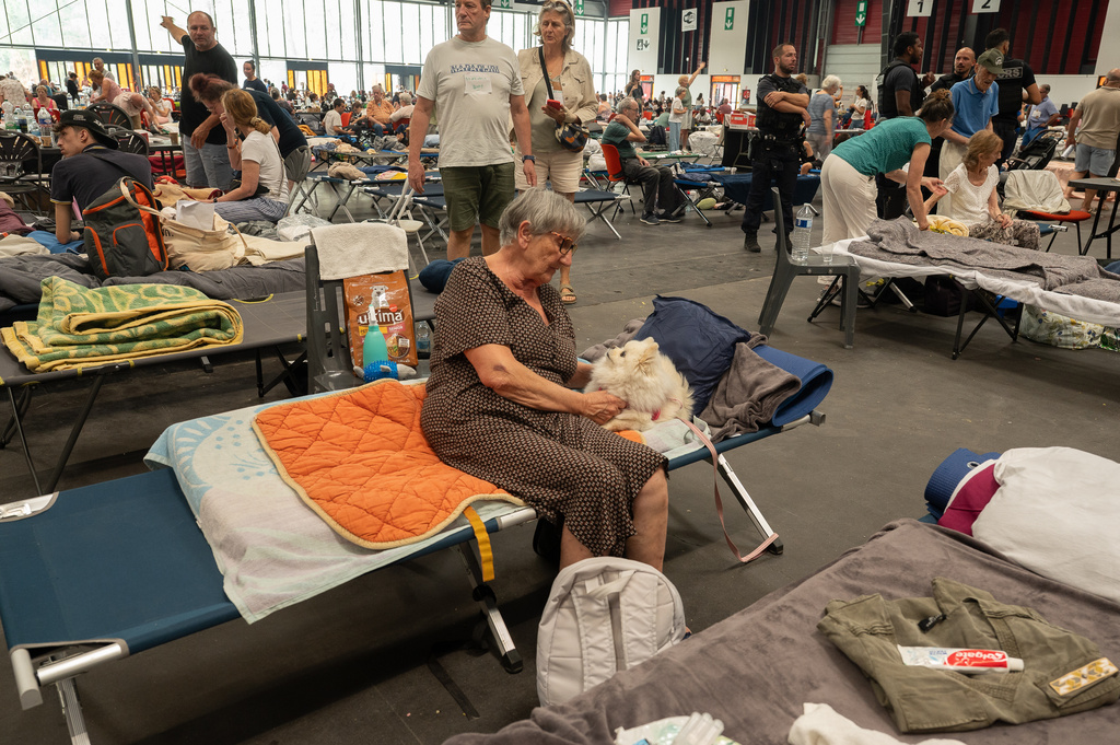 A woman caresses her pet dog at an emergency shelter set up in the Bordeaux Exhibition Centre in Bordeaux, France, for those that had to leave their homes outside town due to the raging wildfires, Sunday, July 26, 2026. (AP Photo/Caroline Blumberg)