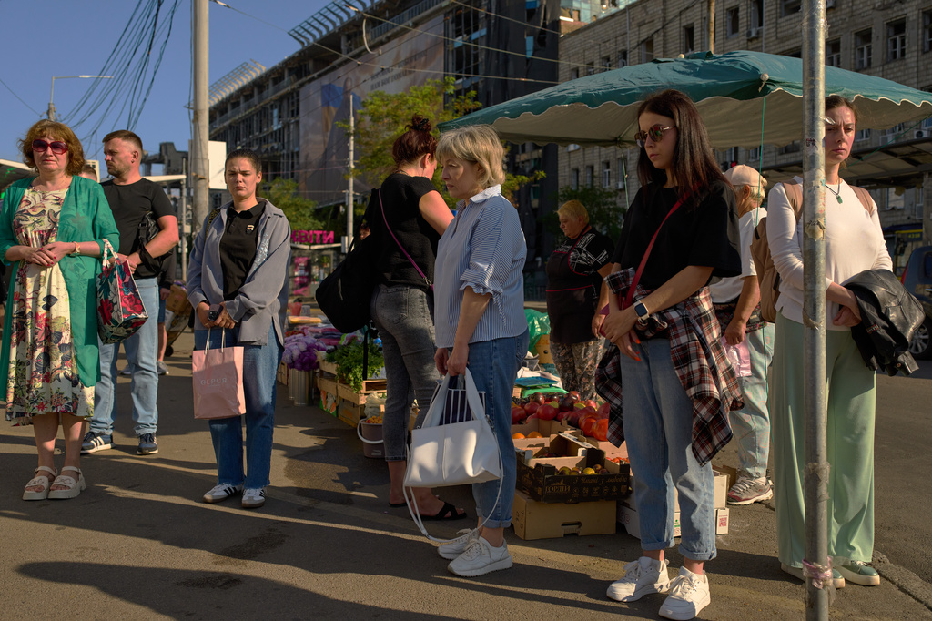 People observe a daily nationwide minute of silence in memory of soldiers killed in the war with Russia, in the Lukianivska neighborhood of Kyiv, Ukraine, Thursday, Aug. 27, 2026. (AP Photo/Francisco Seco)