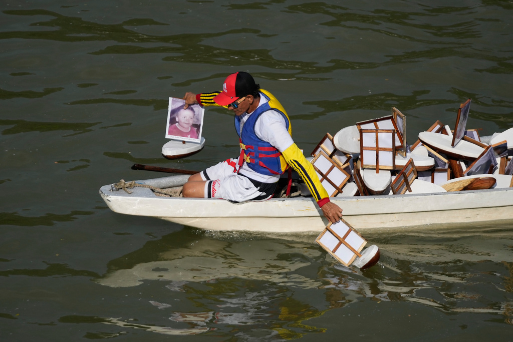A fisherman collects small boats with photos of children missing since the Nevado del Ruiz eruption release, that were released by family members into the Guali River in Honda, Colombia, Wednesday, Nov. 12, 2025, on the eve of the 40th anniversary of the disaster that killed about 25,000 people. (AP Photo/Fernando Vergara)