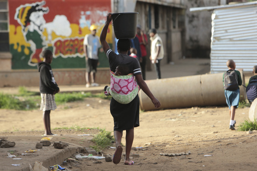 FILE - A woman carries a her baby and a bucket of water in Harare on April 6, 2020. A new study says an African woman is roughly 130 times more likely to die from pregnancy and childbirth complications than a woman in Europe or North America, the U.N. population fund reported Wednesday, April 17, 2024, as it decried widening inequality in sexual and reproductive health and rights worldwide. (AP Photo/Tsvangirayi Mukwazhi, File)